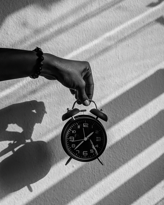 Clock in hand in front of wall